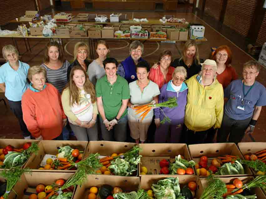 JustFood volunteers and staff posing for a picture in front of packed produce boxes